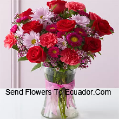 Roses rouges, oeillets rouges et autres fleurs assorties disposées magnifiquement dans un vase en verre