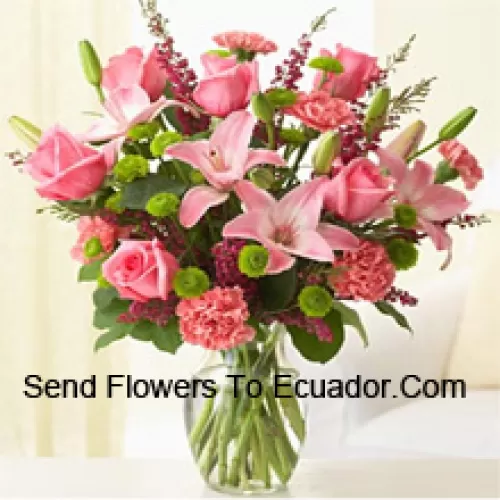 Roses roses, oeillets roses et lys roses avec des fougères assorties et des remplissages dans un vase en verre